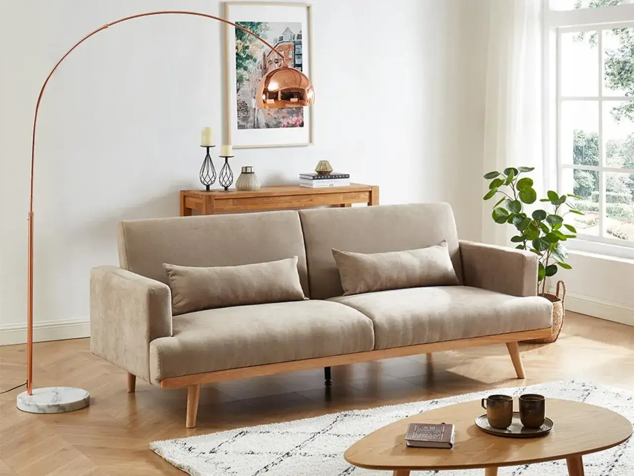 En ljus och inbjudande möblering med en beige soffa, kopparfärgad båglampa och ett runt träbord.