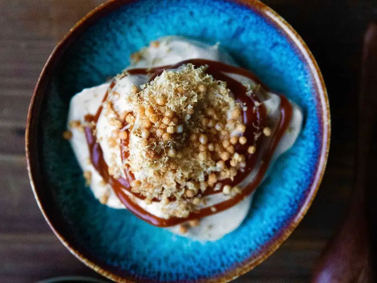 Glass med glass, toppad med krispiga bitar och en generös stråle av kolasås. Ett perfekt recept på kolasås för att lyfta din dessert.