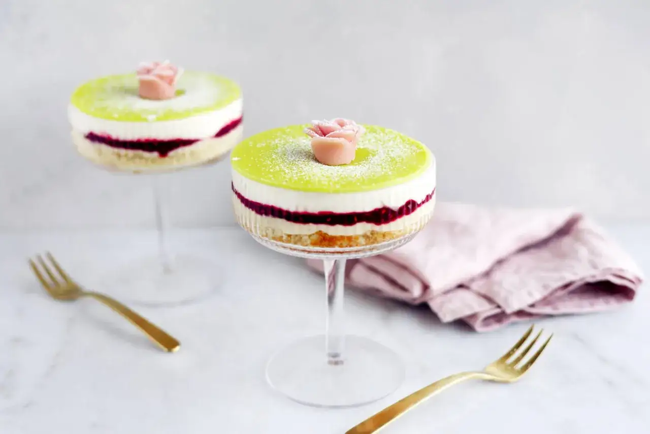 Två vackra prinsesstårtor i glas, dekorerade med en rosa marsipanros och pudrade med florsocker.