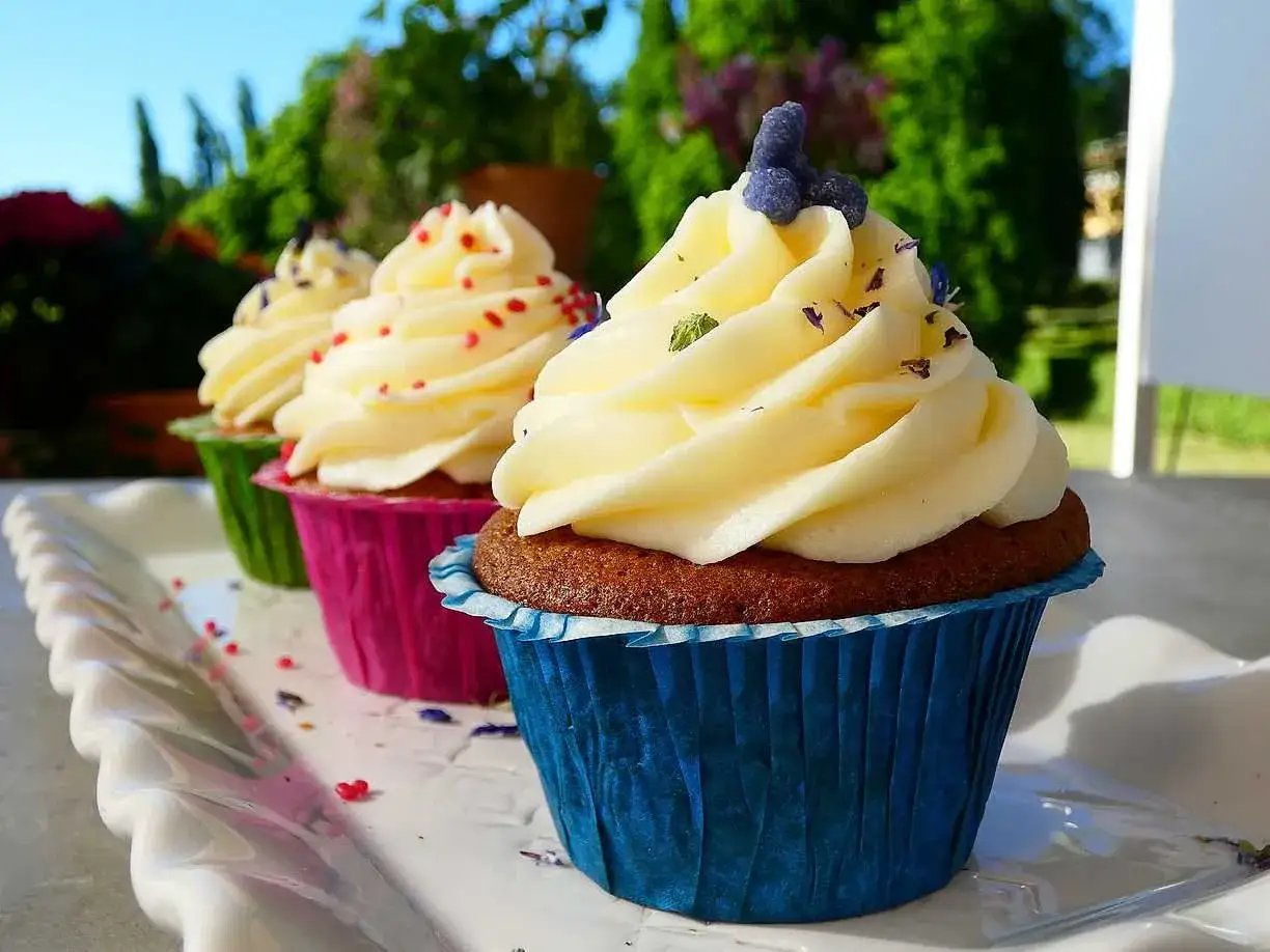 Tre cupcakes med fluffig frosting, dekorerade med strössel och lavendel. Ett perfekt frosting recept för sommaren.