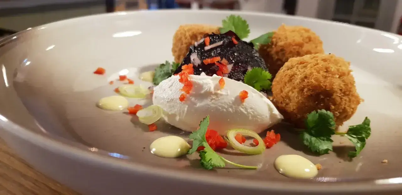 En konstnärlig presentation av ett falafel recept med krämig ost, rödbetor, krispiga bollar och färska örter.