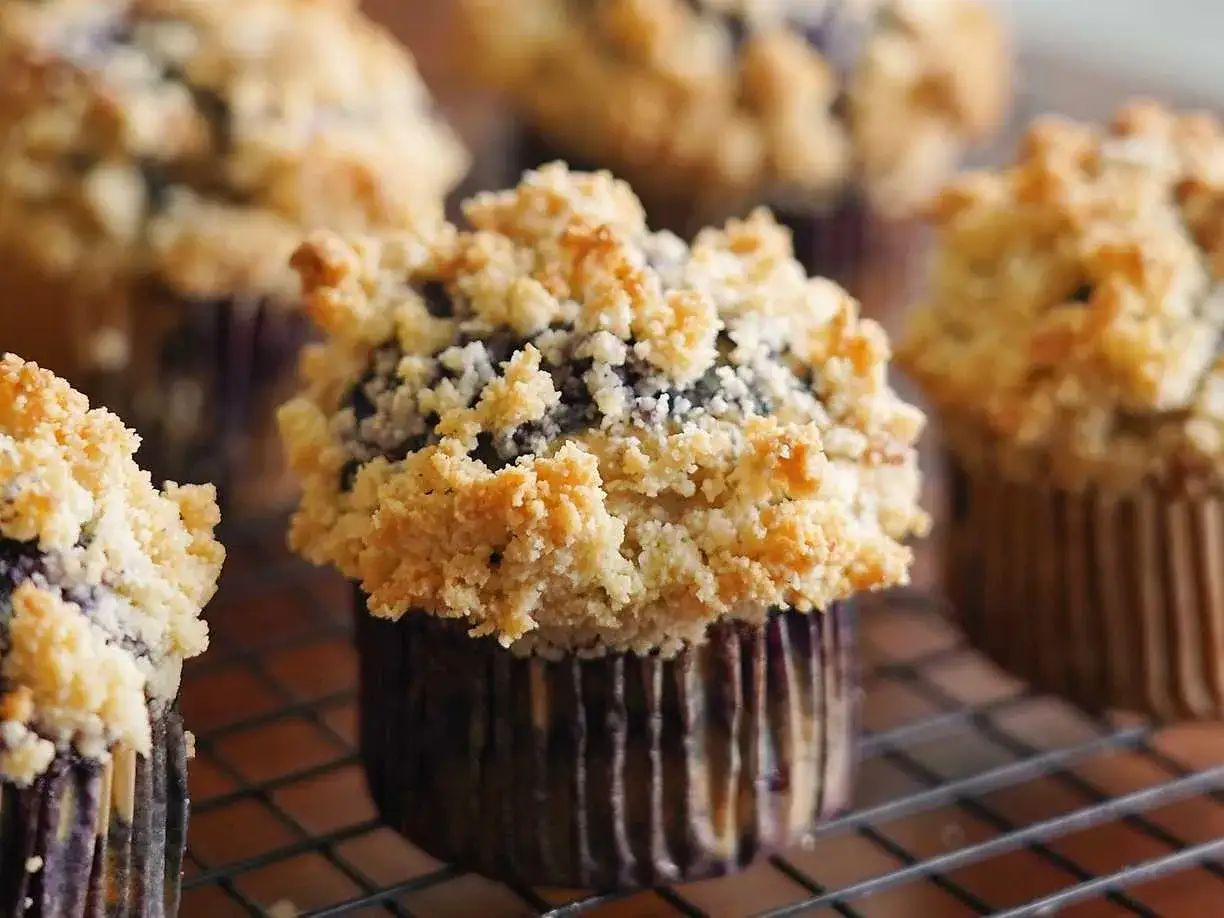 Närbild på fluffiga glutenfria muffins med blåbär och smuldeg. Perfekta för fika!